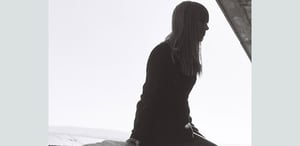 Suvi-Eeva Äikäs pictured in black and white, sitting on a wall