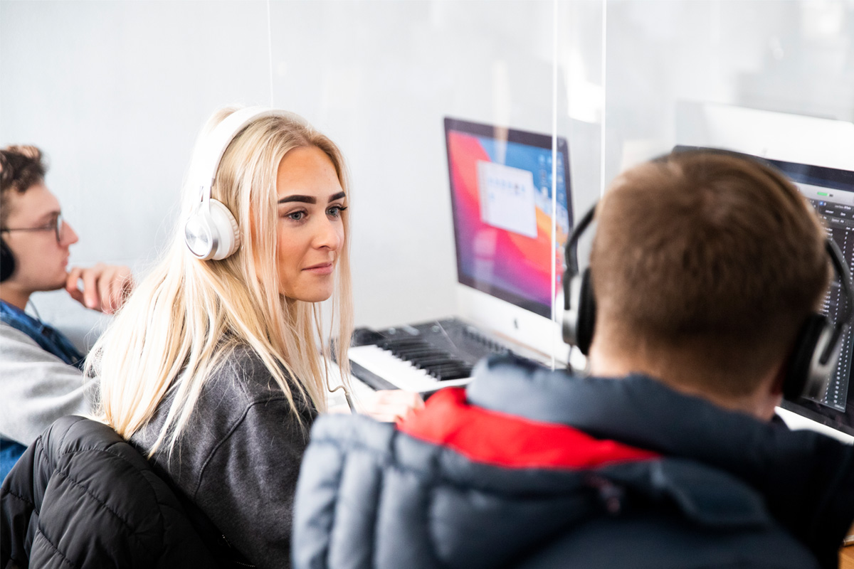 A female student smiling at a male student in an iMac computer suite