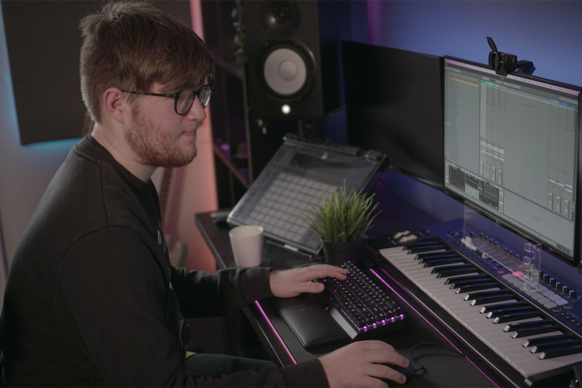 A male student producing music in his home studio