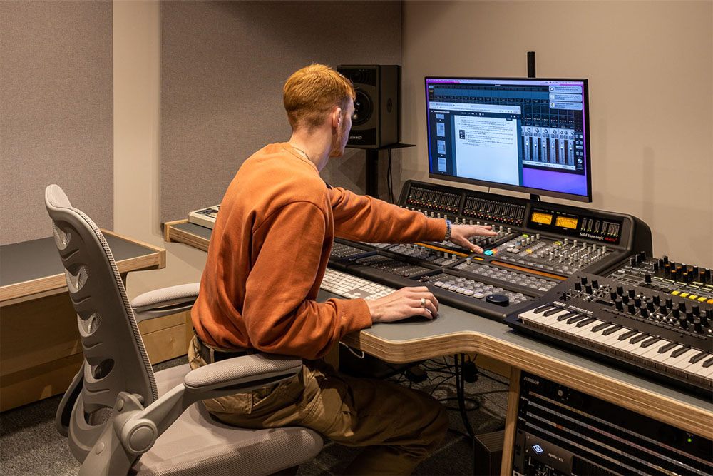 A student operating an SSL mixing console at dBs Manchester_
