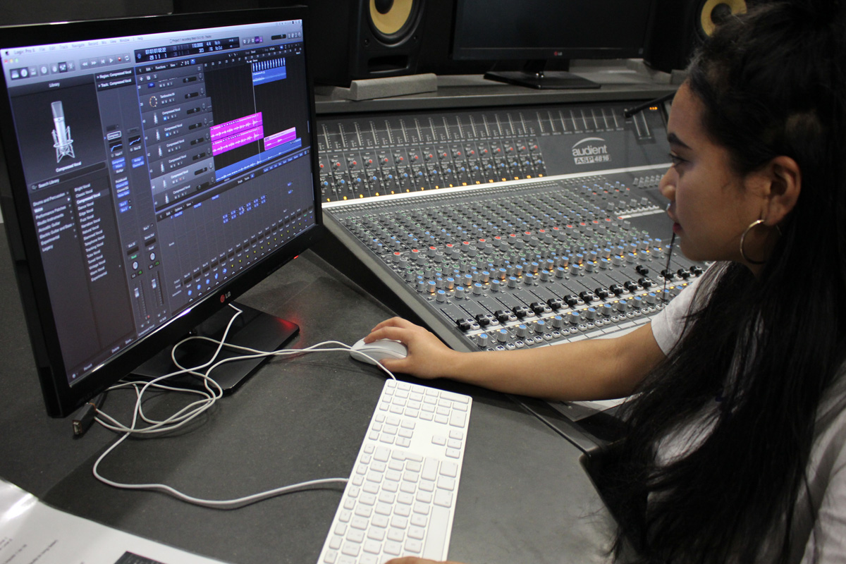 A young female student using Logic Pro X next to the Audient ASP4816 mixing desk