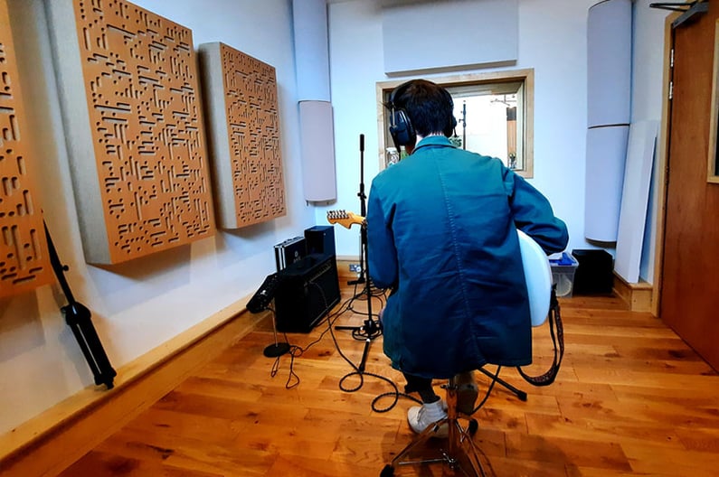 A young male musician playing guitar in the dBs Pro live room