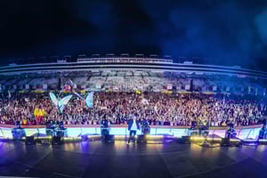 A night time photo of Aiden Morgan (DNMO) on stage with an enormous crowd of people behind him