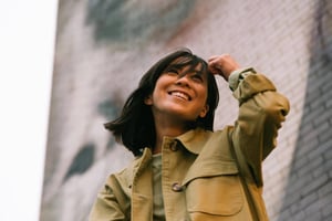 A press shot of Manami in front of a graffiti'd brick wall