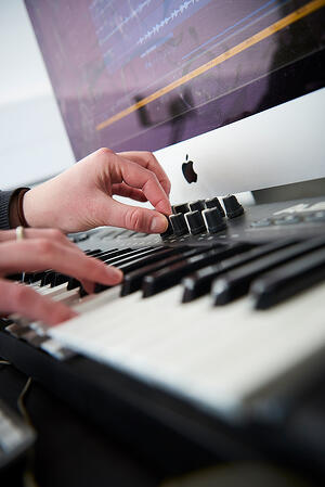 A close-up of someones hands as they play a MIDI keyboard using Logic Pro X - Get a High-Quality Music Degree Without Breaking the Bank