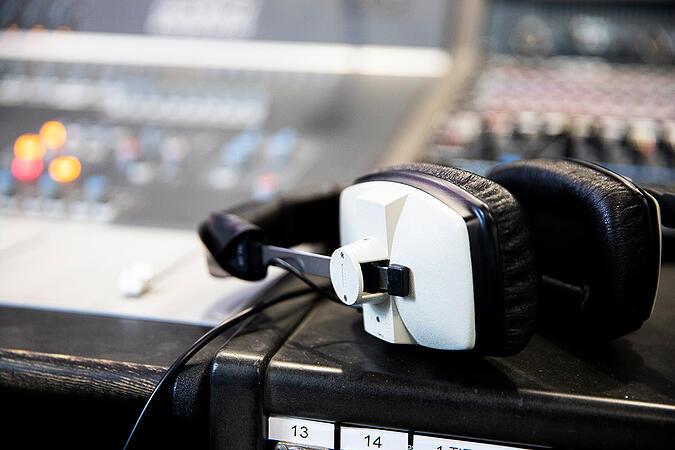 A pair of white headphones resting on top of a mixing desk - Online Study at dBs- Get a High-Quality Music Degree Without Breaking the Bank