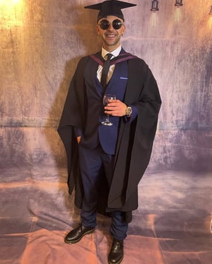 Ché Leader in his graduation gown and mortarboard at Watershed
