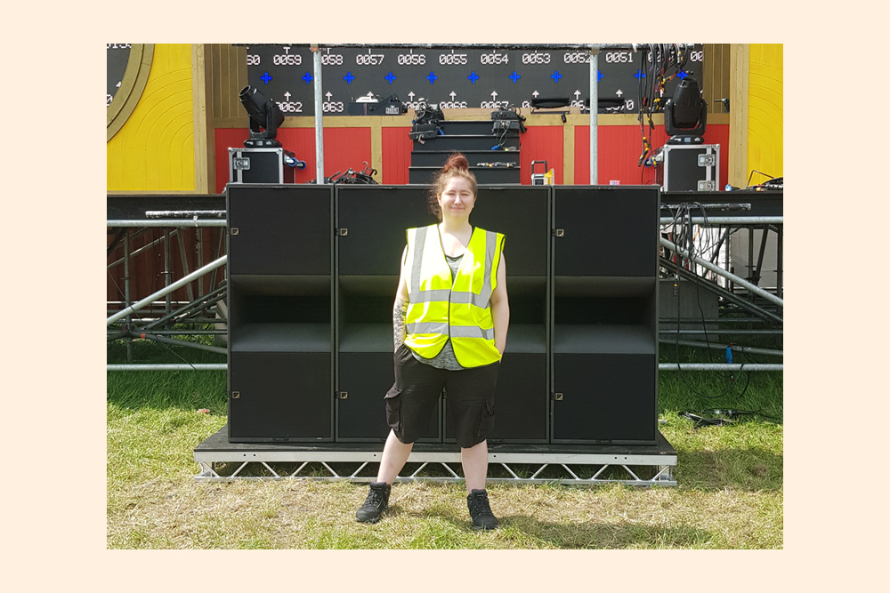 Hazel standing in front of a speaker stack at Summer of Love festival