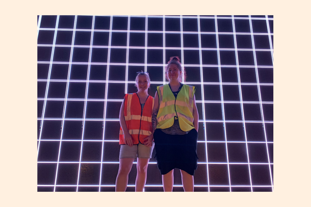 Skye and Hazel standing in front of an illuminated frame at Summer of Love festival